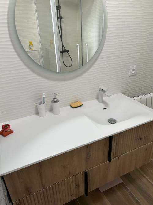 Modern bathroom vanity with white sink, chrome faucet, and round mirror at Dream Properties in La Plagne Tarentaise