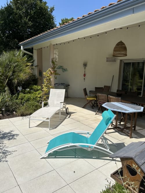 Sunny patio at Dream Properties with turquoise loungers, dining furniture, and landscaped garden in La Plagne Tarentaise