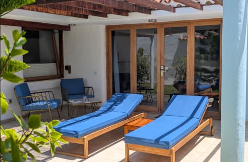 Birdcage Resort Garden Suite patio with blue loungers, wooden chairs, and ocean views in Playa del Inglés