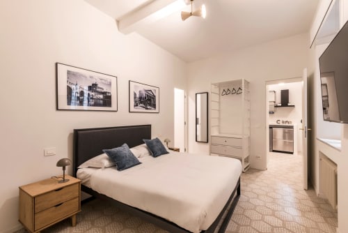 Camera moderna in Flavia's Holiday Home a Roma con letto, comodino, quadri in cornice nera, angolo cottura e arredamento beige