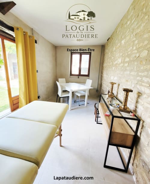 Espace bien-être du Logis de la Pataudière B&B à Champigny-sur-Veude avec lits de massage, table à manger et mur en pierre