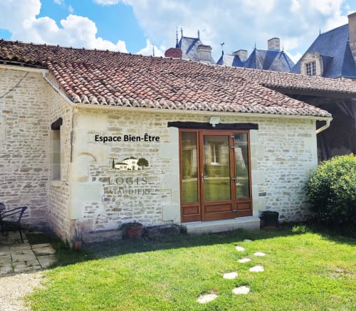 Entrée de l'Espace Bien-Être au Logis de la Pataudière, bâtisse en pierre aux toits de tuiles en Champigny-sur-Veude