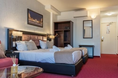 Modernes Hotelzimmer im Hotel Royal Paris Ivry mit Queensize-Bett, rotem Teppich und zeitgenössischen Möbeln