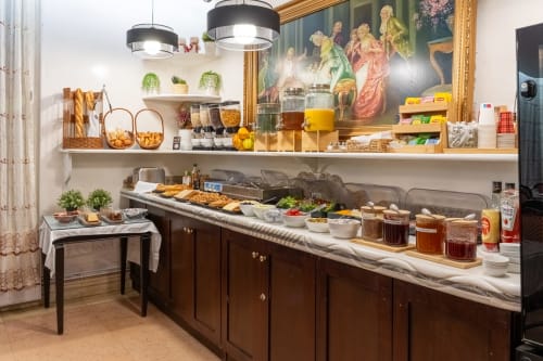 Frühstücksbuffet des Hotel Royal Paris Ivry mit Gebäck, Marmeladen und Getränken auf dunklem Holztresen