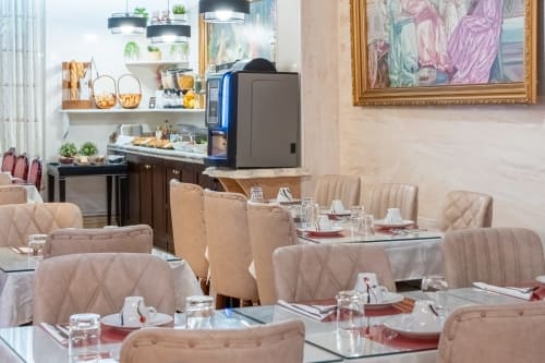 Elegantes Hotelspeisezimmer im Hotel Royal Paris Ivry mit beigen gesteppten Stühlen, Glastischen und moderner Küche