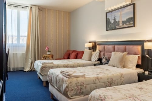 Camera tripla dell'Hotel Royal Paris Ivry con tre letti, testata rosa, carta da parati a righe e moquette blu a Ivry-sur-Seine
