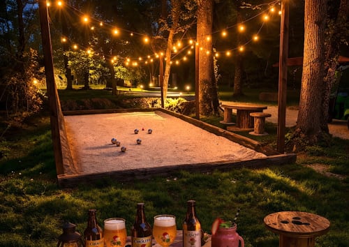 Beleuchteter Boccia-Platz in Les Lodges de Vaugrigneuse mit Lichterketten, Bieren und rustikalem Mobiliar in Vaugrigneuse,