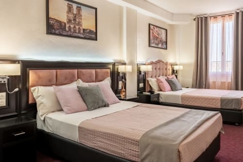Elegante camera dell'Hotel Royal Paris Ivry con letti gemelli, testiere rosa e opere d'arte parigina