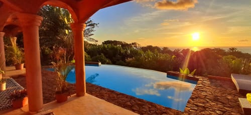 La piscina a sfioro di La Villa Ankarena al tramonto che si affaccia sul giardino tropicale e il mare, Madagascar