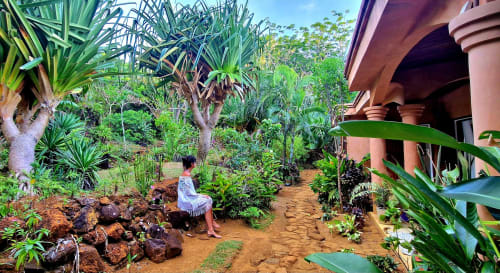 Sentiero del giardino tropicale di La Villa Boraha, Madagascar, con rigogliose palme e architettura in terracotta
