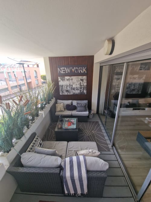 Terrasse moderne à Zoppas Aix-les-Bains avec vue sur la ville, œuvre new-yorkaise et chaises longues confortables