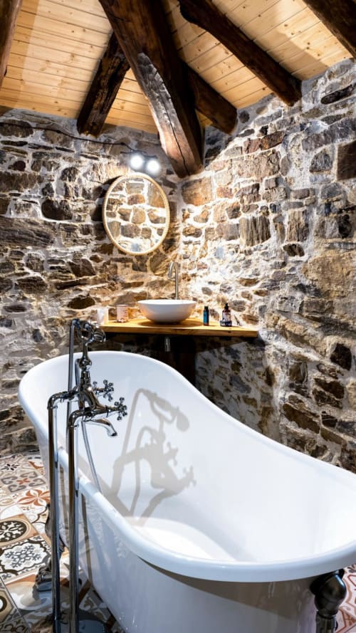 Baño rústico de piedra con bañera independiente blanca, vigas de madera y vistas a las montañas en La Casa Antollos, Baralla