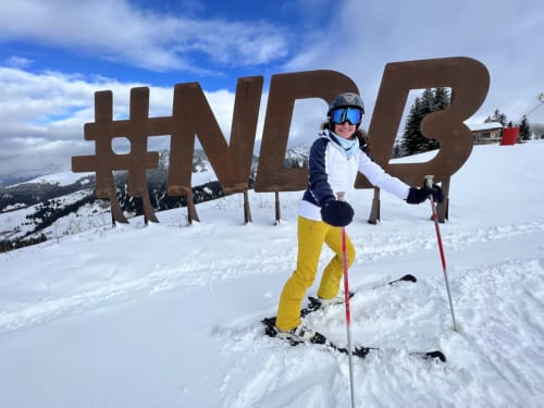 Skier at Chez Francine resort in Notre Dame de Bellecombe with #NWL5 sign and snowy mountains