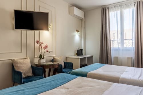 Camera moderna all'Hotel Royal Paris Ivry con letti gemelli, accenti blu, TV e vista parigina