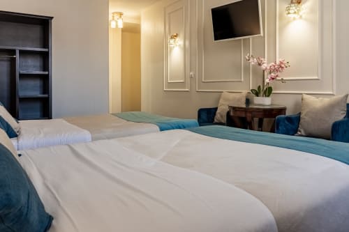 Camera moderna dell'Hotel Royal Paris Ivry con due letti, arredamento elegante, TV a parete e fiori rosa sul comodino