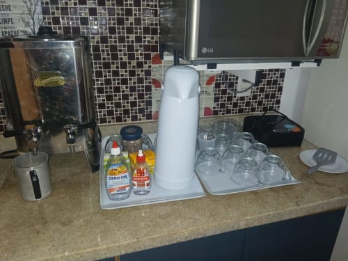 Kitchenette da suíte Rio Vibes Hostel com bebedouro, copos e garrafas de bebidas no balcão