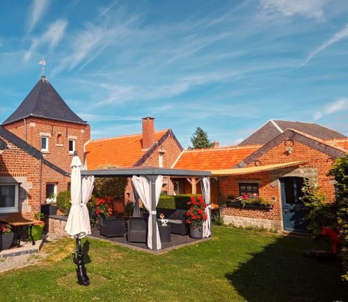 Au Repos De La Licorne brick B&B with gazebo seating and red-roofed buildings in Gommegnies, France