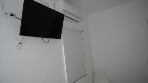 Televisor plano montado en la pared con cables en una habitación de huéspedes del Hostal Merino Jédula, Cádiz, España