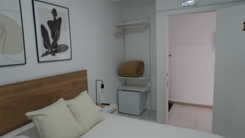 Luminosa habitación doble en Hostal Merino Jédula con cabecero de madera, almohadas blancas, arte moderno en la pared y baño privado