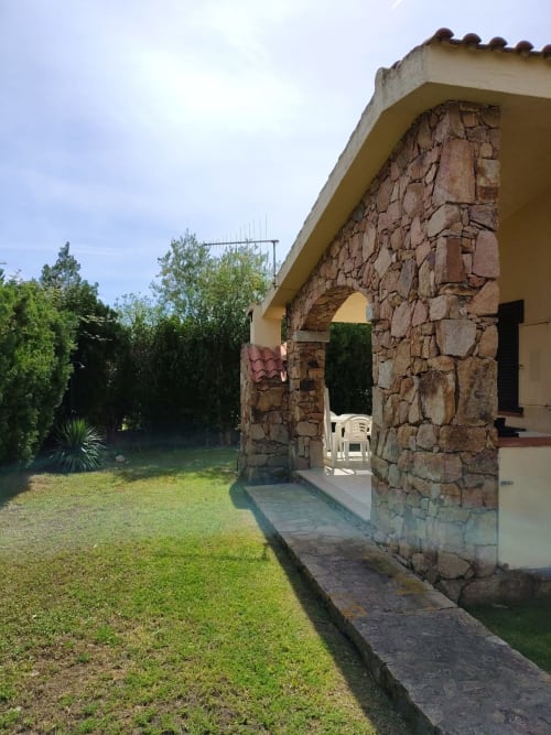 Cottage in pietra con ingresso ad arco, cornici gialle, terrazza giardino e rigogliosa vegetazione presso Oasi Villetta Adriana, San Teodoro
