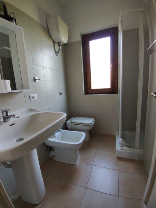 Modern bathroom in Oasi Villetta Adriana at Holidays San Teodoro with sink, toilet, bidet, shower enclosure and bright window