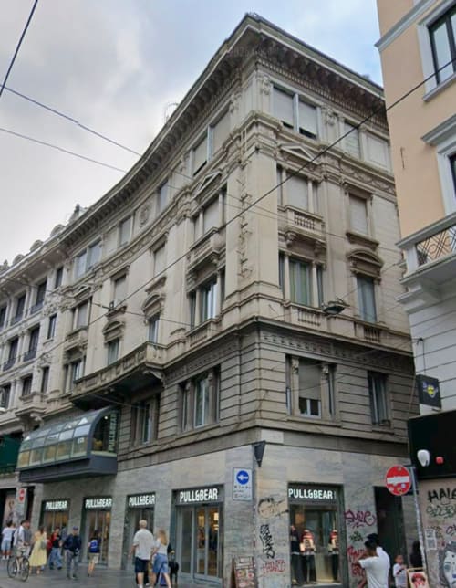 Edificio storico di Milano con facciata ornamentale, negozi al piano terra, hotel Maisons Milano nel cuore della città
