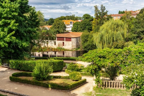 Jardines de Aldea Rural Santo André con molino de piedra histórico, setos cuidados y paisaje rural de Ourense