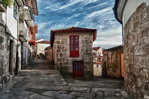 Calle de piedra en la aldea rural Santo André con edificio de puerta roja en Congostro, Ourense, España