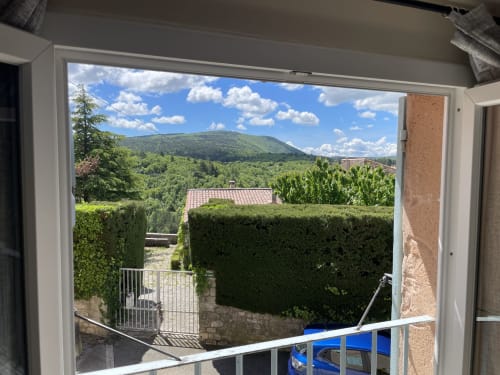 Vue panoramique depuis le balcon du studio Hôtel d'Albion à Sault, avec haies verdoyantes et pics distants