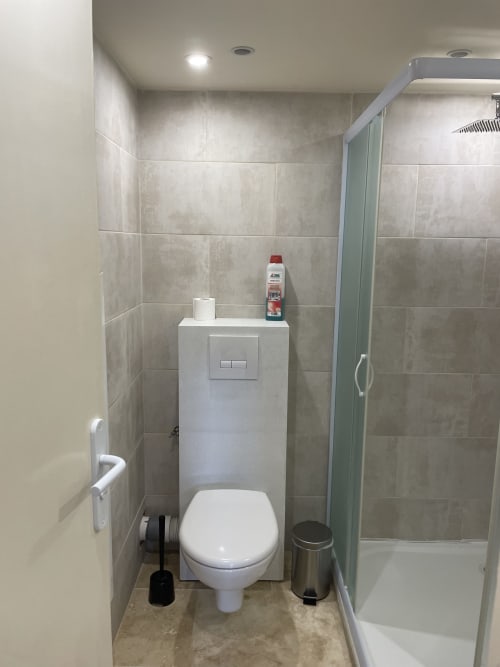 Salle de bain moderne avec toilettes, lavabo mural et douche à l'Hôtel d'Albion studio à Sault