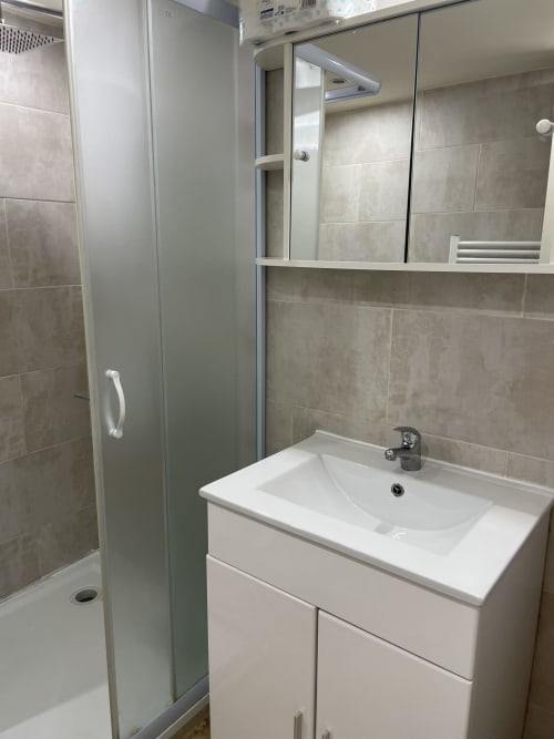 Salle de bain moderne avec vanité blanche, lavabo et douche vitrée à l'Hôtel d'Albion, Sault