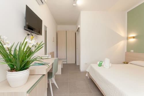 Modern hotel room at Le Dune Relax in San Teodoro with queen bed, desk, flat-screen TV, and pool view