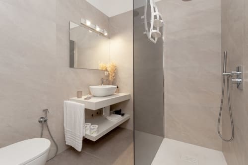 Modern bathroom at Le Dune Relax hotel in San Teodoro with vessel sink, mirror, shower, and heated towel rack