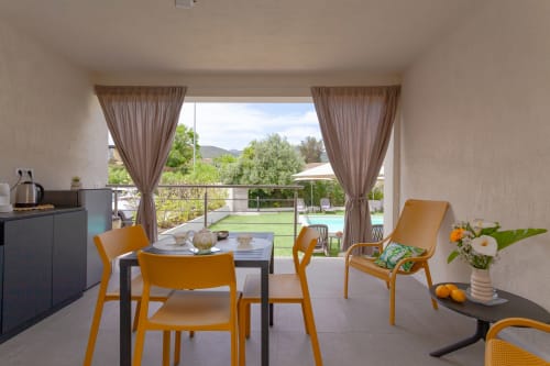 Modern hotel room at Le Dune Relax with pool view balcony, orange chairs, and mountain landscape in San Teodoro