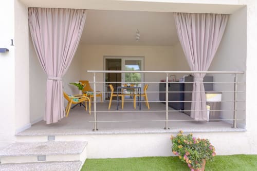 Modern balcony room with dining area, yellow chairs, pink curtains and pool view at Le Dune Relax, San Teodoro