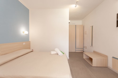 Modern bedroom at Le Dune Relax hotel in San Teodoro with king bed, wooden furniture, and pool view balcony