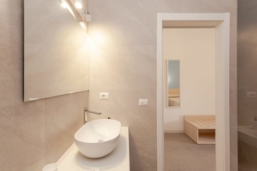 Modern bathroom with white round sink and mirror at Le Dune Relax hotel in San Teodoro, Italy