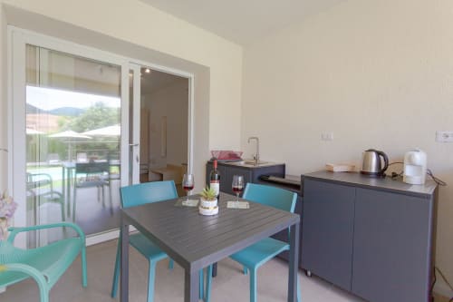 Modern dining area with turquoise chairs, dark table, and pool view balcony at Le Dune Relax hotel, San Teodoro