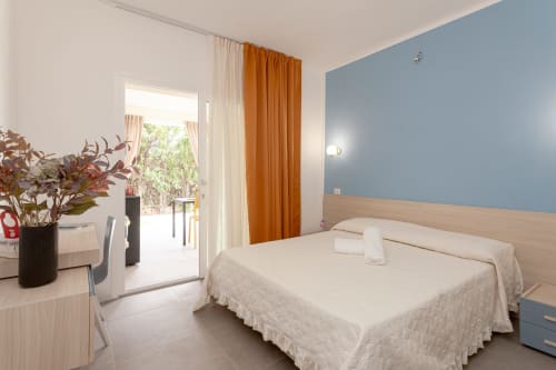 King deluxe bedroom at Le Dune Relax hotel in San Teodoro with blue accent wall, garden view, and modern amenities