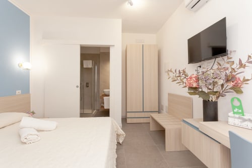 Modern hotel room at Le Dune Relax with queen bed, flat-screen TV, wooden furniture and ensuite bathroom