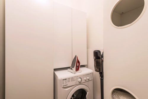 Lavanderia nella Casa Vacanze di Flavia a Roma con lavatrice, ferro da stiro e specchio