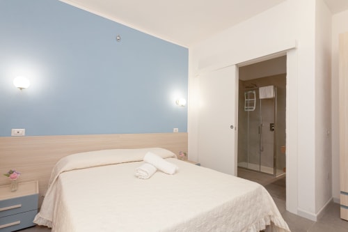 King deluxe bedroom at Le Dune Relax hotel in San Teodoro with blue accent wall, en-suite bathroom, and modern furnishings