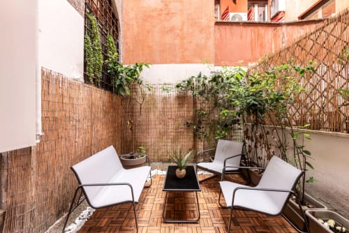 Accogliente patio nel cortile di Flavia's Holiday Home a Roma con sedie a sdraio, piante e pavimento in legno