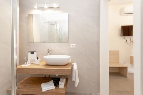 Modern bathroom with white vessel sink and wooden vanity at Le Dune Relax hotel in San Teodoro, Italy