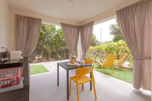 King deluxe room with garden view at Le Dune Relax hotel in San Teodoro, featuring modern seating area and patio access