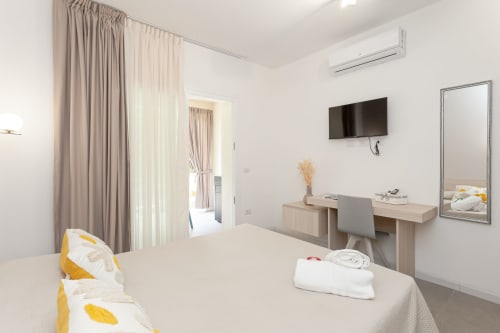 Modern king deluxe bedroom at Le Dune Relax with garden view, TV, desk, and light wood furnishings