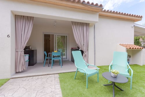 King deluxe room patio at Le Dune Relax hotel in San Teodoro with garden view, turquoise loungers, and direct terrace access.