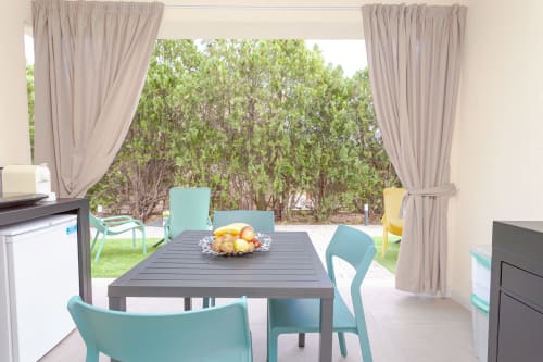 King deluxe balcony with turquoise chairs, dining table, and garden view at Le Dune Relax, San Teodoro