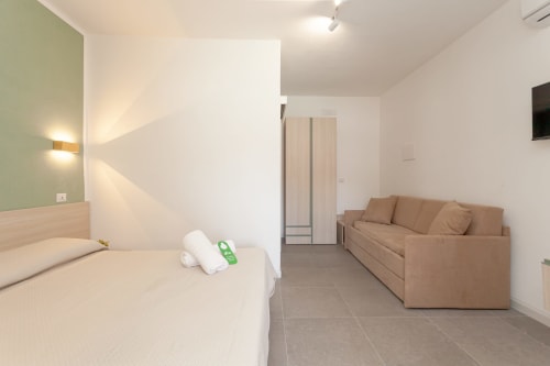 Spacious quadrupla room at Le Dune Relax hotel with bed, sofa, AC, TV and pool views in San Teodoro