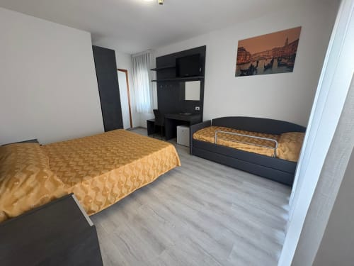 Hotel Panorama quad room in Lido di Jesolo with two beds, flat-screen TV, and modern black furnishings